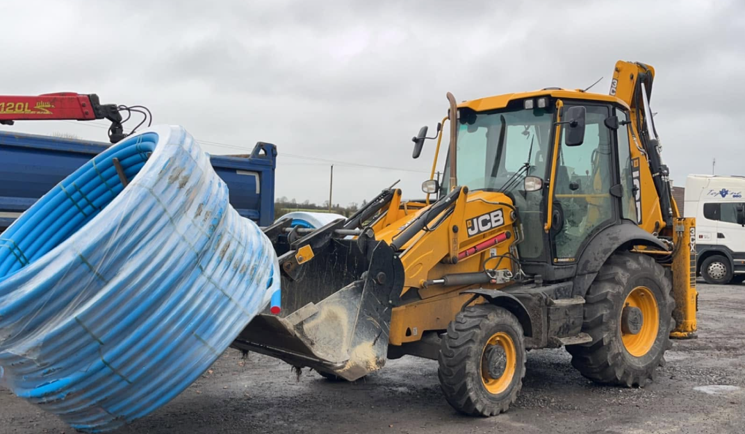 JCB backhoe loading blue pipe coil